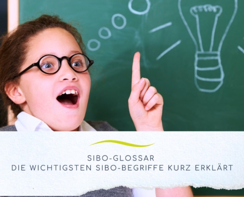 Mädchen das vor einer Schultafel den Finger hebt